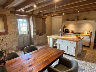 Cuisine équipée ouverte avec îlot central et table à manger sur sol en calade à Le Coux-et-Bigaroque