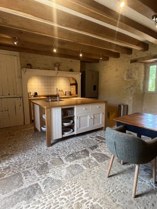 Intérieur moderne avec pierres apparentes et poutres en bois de la location de vacances Lou Cantou en Dordogne.