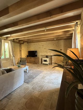 Vue d'ensemble du salon chaleureux avec poêle, pierres apparentes et sol en travertin au gîte Lou Cantou à Le Coux-et-Bigaroque