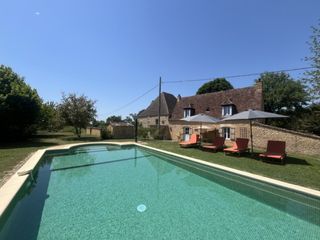Vue d'ensemble de la maison de vacances en pierre et sa grande piscine privée entourée par la nature