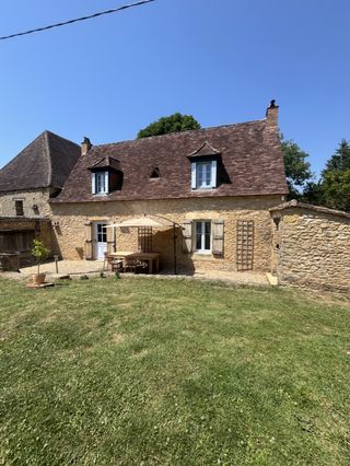 Façade authentique en pierre blonde du Périgord et jardin arboré du gîte Lou Cantou